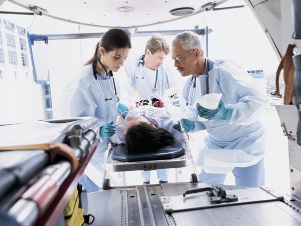 Medical team attending to a patient on a stretcher in an ambulance.