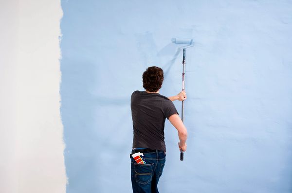 Man rolling light blue paint.
