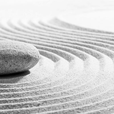 Zen garden stone with raked sand patterns symbolizing tranquility.