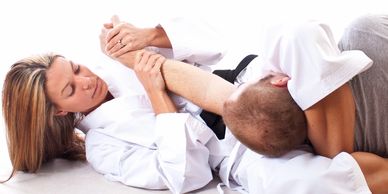 Two martial artists practicing a grappling technique on the floor.