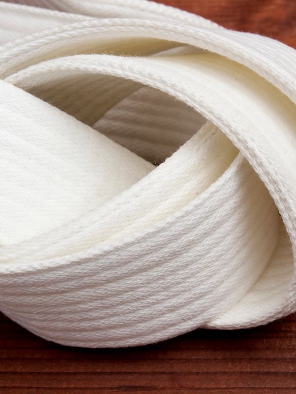 Close-up of a white martial arts belt coiled on a wooden surface.