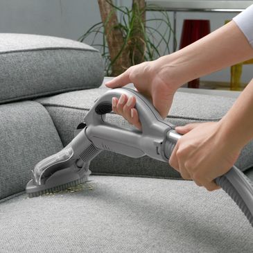 Woman with handheld vacuum cleaning on sofa