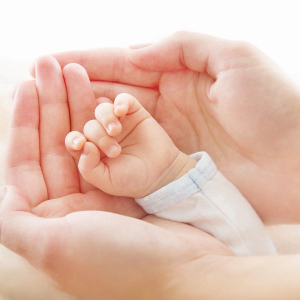 Adult hands gently holding a baby's hand, symbolizing care and protection.
