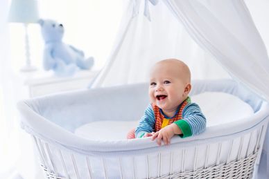 A newborn in a crib smiling 
