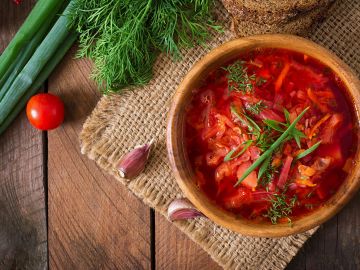 Traditional bowl of borscht with fresh herbs and garlic.