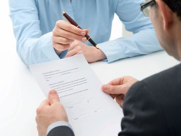 Person pointing to a document section for signing.