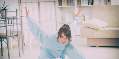 Woman practicing Tai Chi in a bright room.