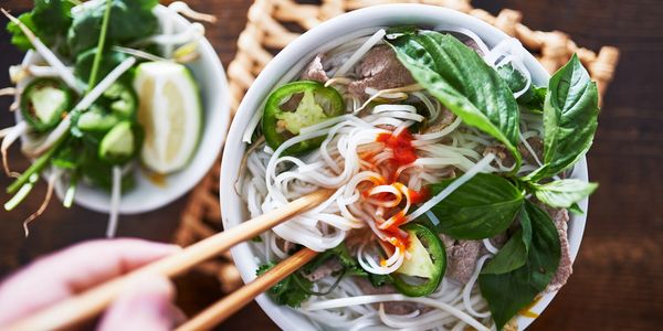 Delicious pho noodle soup with side vegetable and herbs