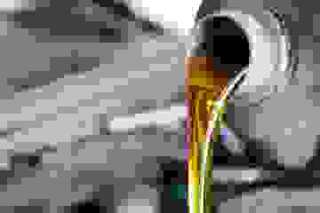 Automotive oil being poured out of a gray plastic bottle.