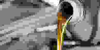 Automotive oil being poured out of a gray bottle.