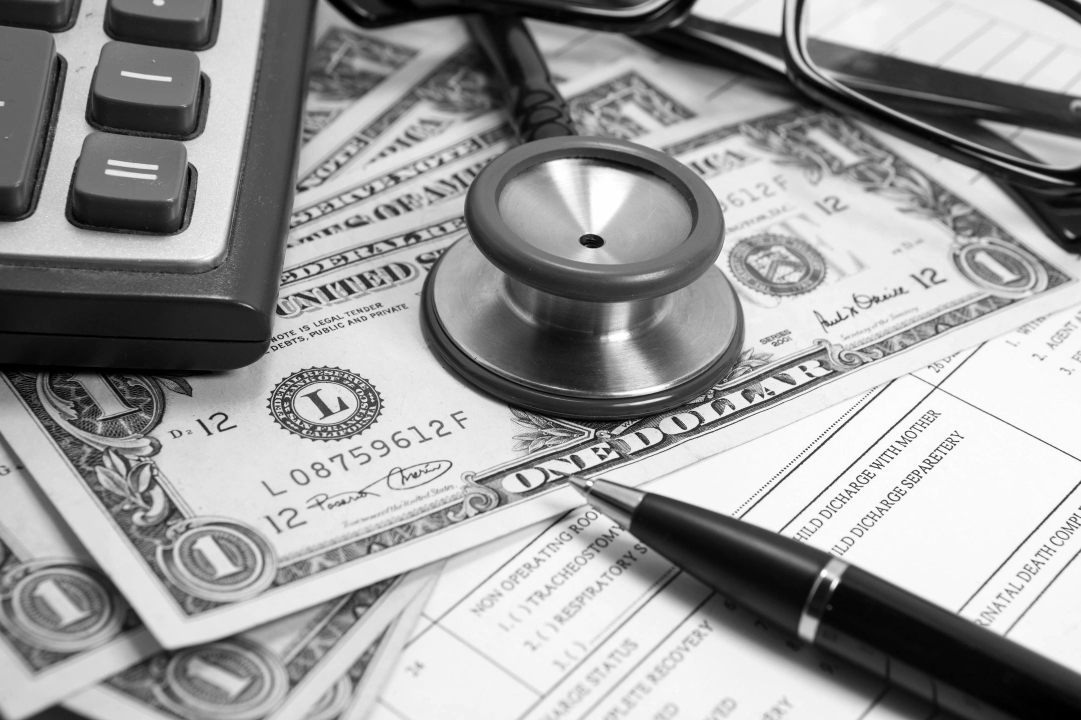 Medical stethoscope on top of money with a calculator and sheet of medical bills.