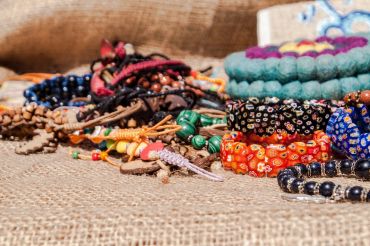 Colorful handmade bracelets displayed on burlap fabric.