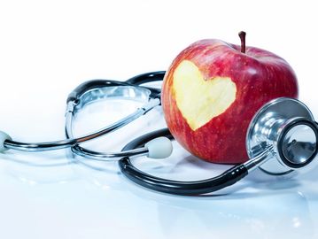 an image of a stethoscope wrapped around an apple with a heart shaped carving. 