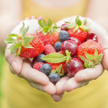 someone holding a handful of strawberries and blueberrries