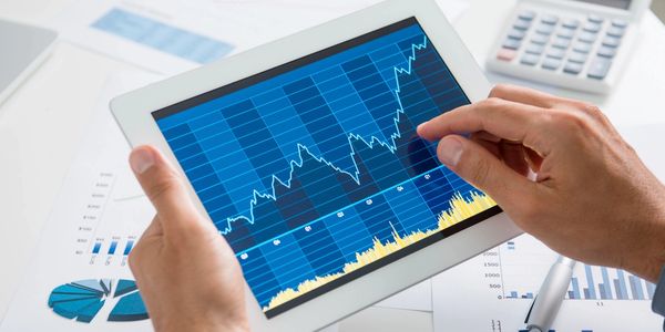 Person analyzing financial data on a tablet showing upward stock trends.