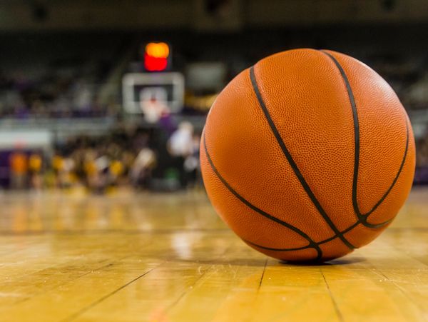 Close-up of a basketball on a court with a blurred hoop in the background.