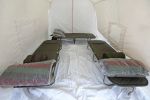 Inside view of a tent with three cots and pillows.