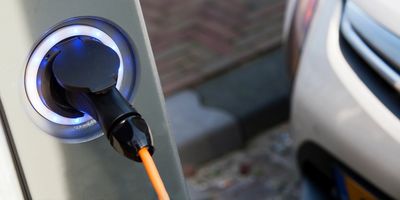 Electric car plugged in and charging at a station.