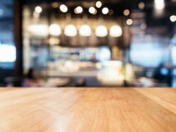 Empty wooden table with blurred cafe background.