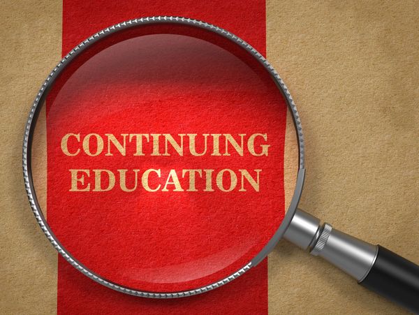 Magnifying glass highlighting the words 'Continuing Education' on a red and brown background.