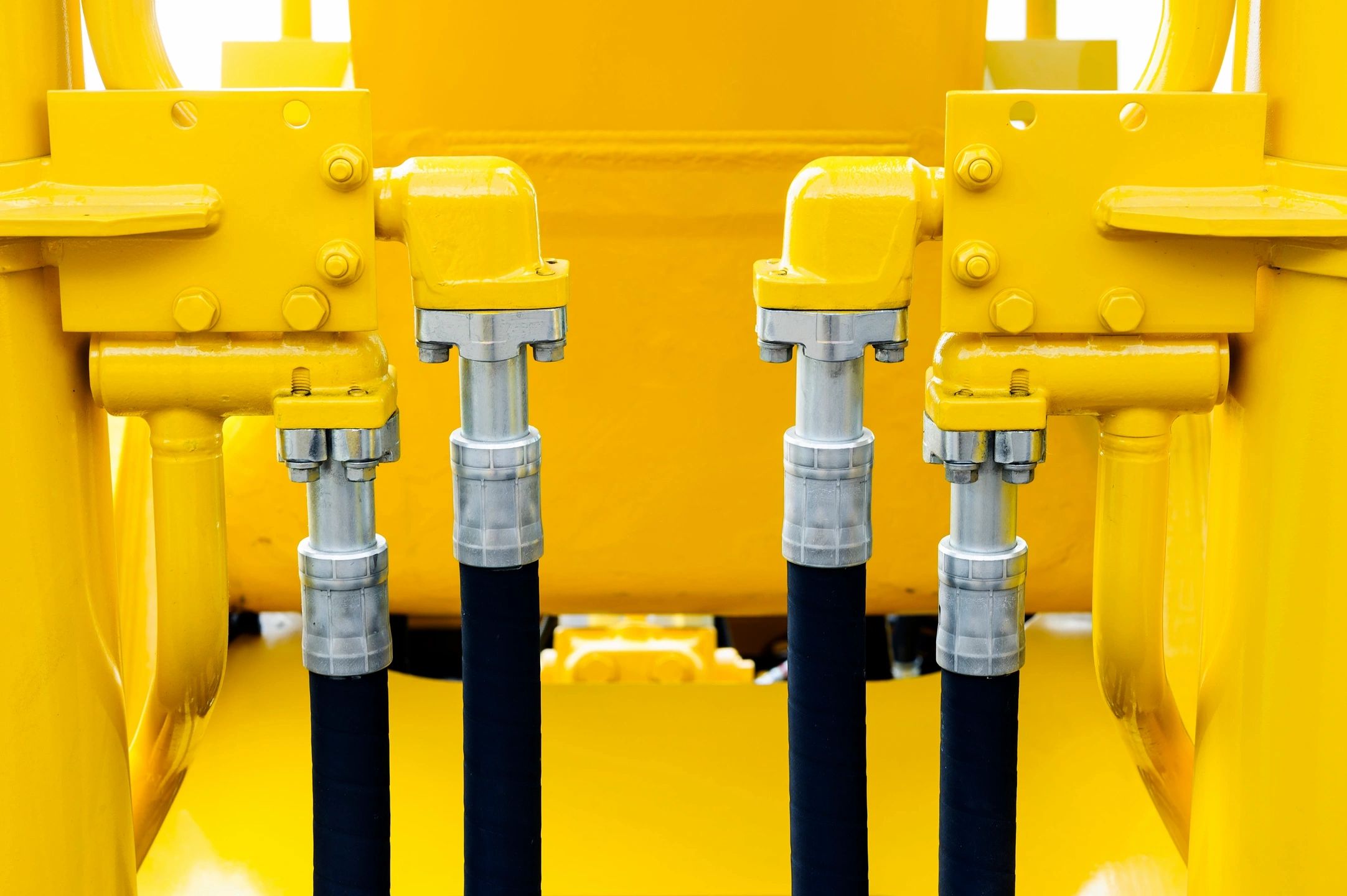 Close-up of hydraulic hoses and connectors on yellow machinery.