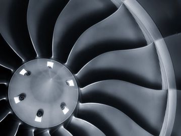 Close-up of a sleek aircraft turbine engine fan with curved blades.
