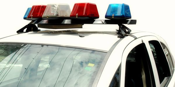 Close-up of a police car's rooftop with red, blue, and white emergency lights.