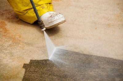 A pressure washing guy cleaning a very dirty cement surface.
