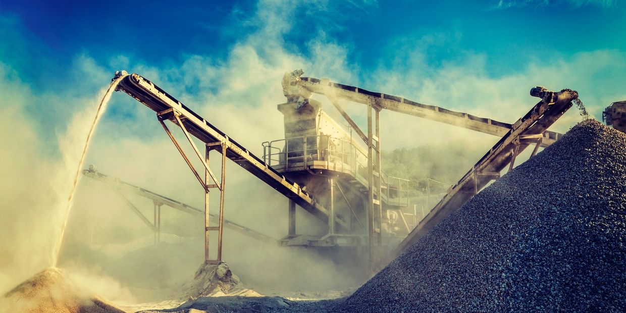 Industrial conveyor belts moving gravel and sand at a dusty quarry site.