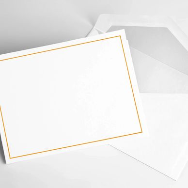Blank white card with gold border next to an open envelope.
