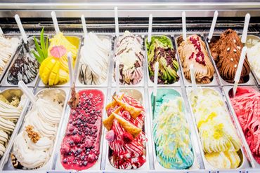 Assorted colorful rolled ice cream flavors in a display case.