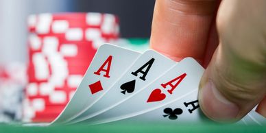 A poker table with chips in the background and a hand showing four aces.
