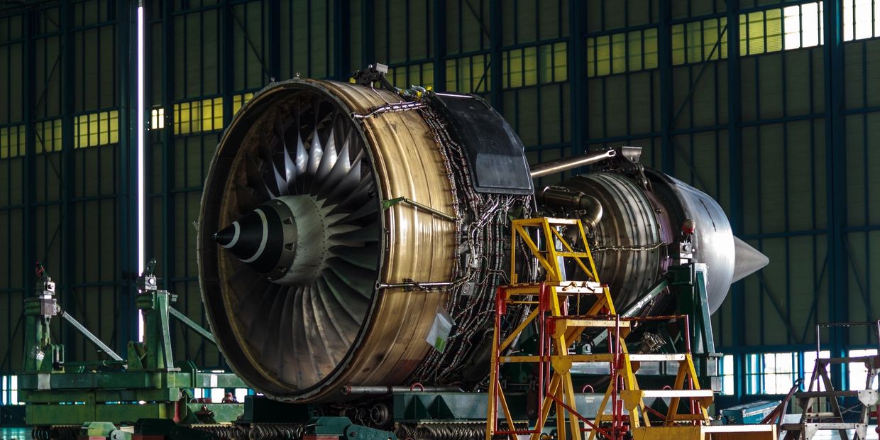 A large jet engine inside an aircraft hangar with maintenance equipment.