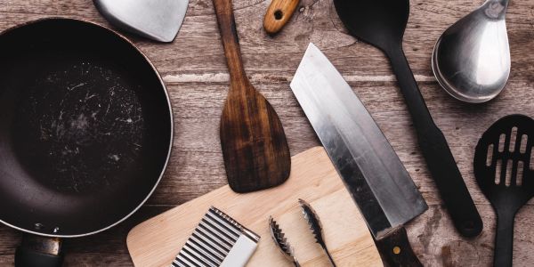 Wooden and metal kitchen tools on a rustic wooden surface.