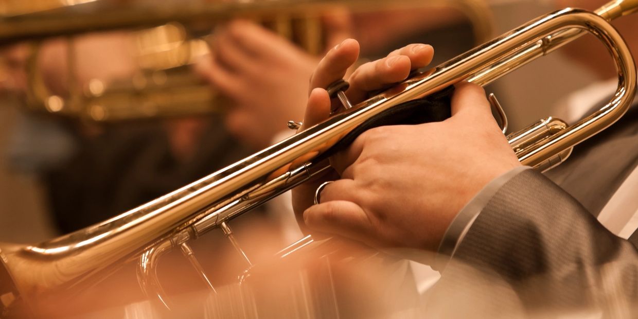 Hands playing a brass trumpet.