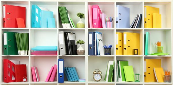 Colorful organized office shelves with various binders and stationery items.