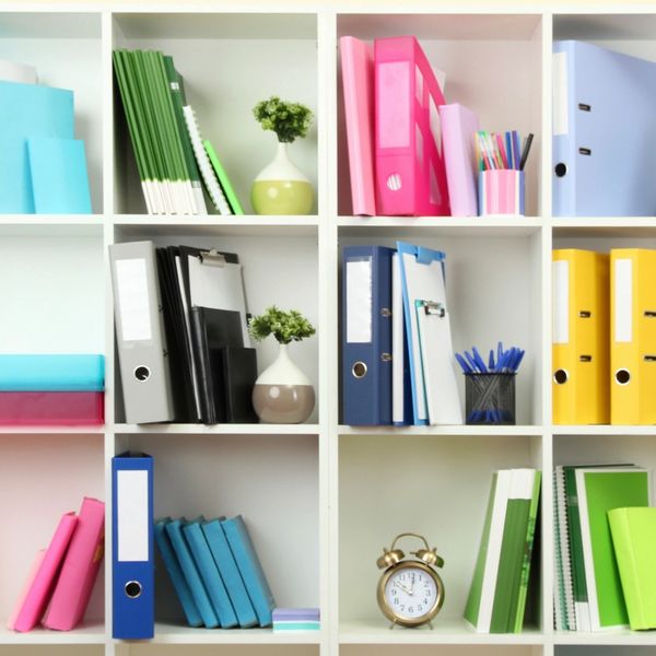 White bookshelf with colorful binders and books. 