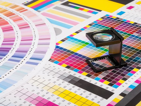 Color calibration charts and a magnifying glass for print quality inspection.