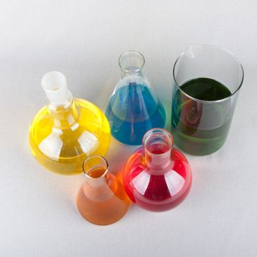 Stock photo of several lab containers containing colored liquids. 