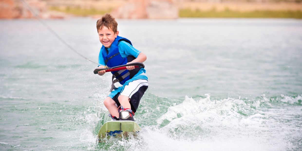 Kid smiling while riding on water skis  