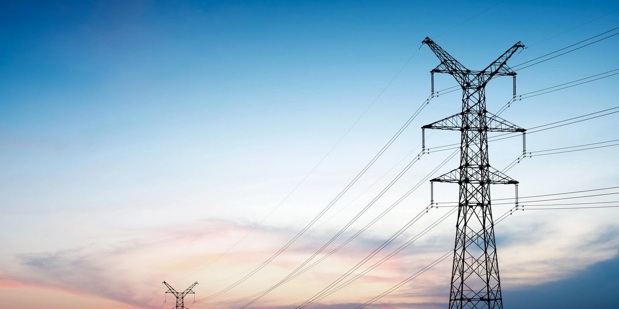 Electrical transmission towers against a calm dusk sky.