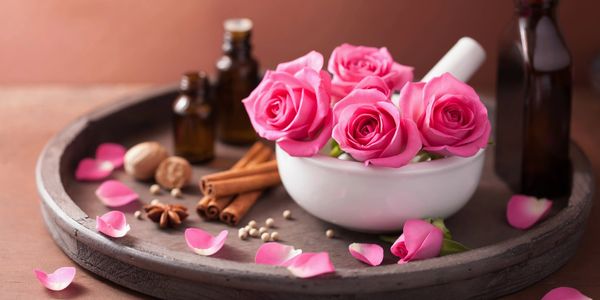 Bottles of oils and a bowl of roses