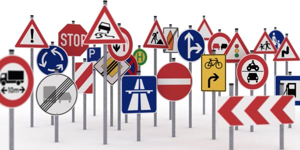 A crowded cluster of diverse traffic signs on white background.