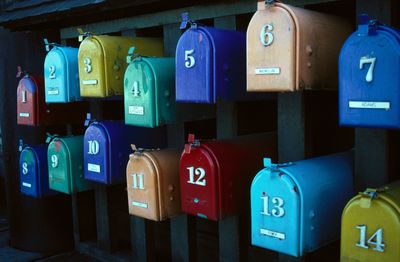 Colorful numbered mailboxes arranged in two rows on a wooden stand.