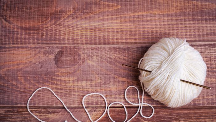 Balle de laine blanche avec un crochet sur du bois