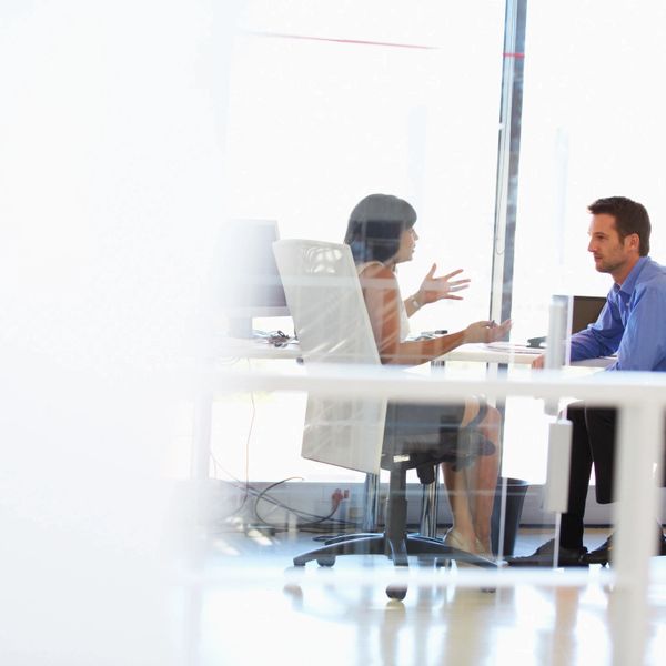 Two professionals engaged in a discussion in a modern office setting.