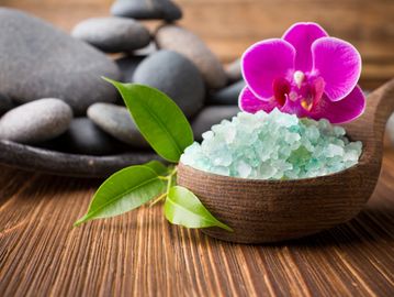 Scoop with large salt, orchid on salt and rocks in the background. 