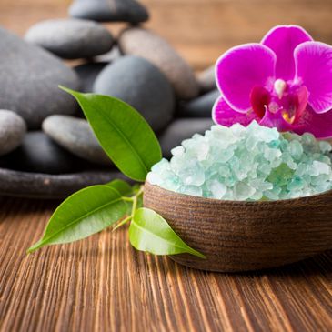 Spa scene with purple flower, bath salts and massage stones. 