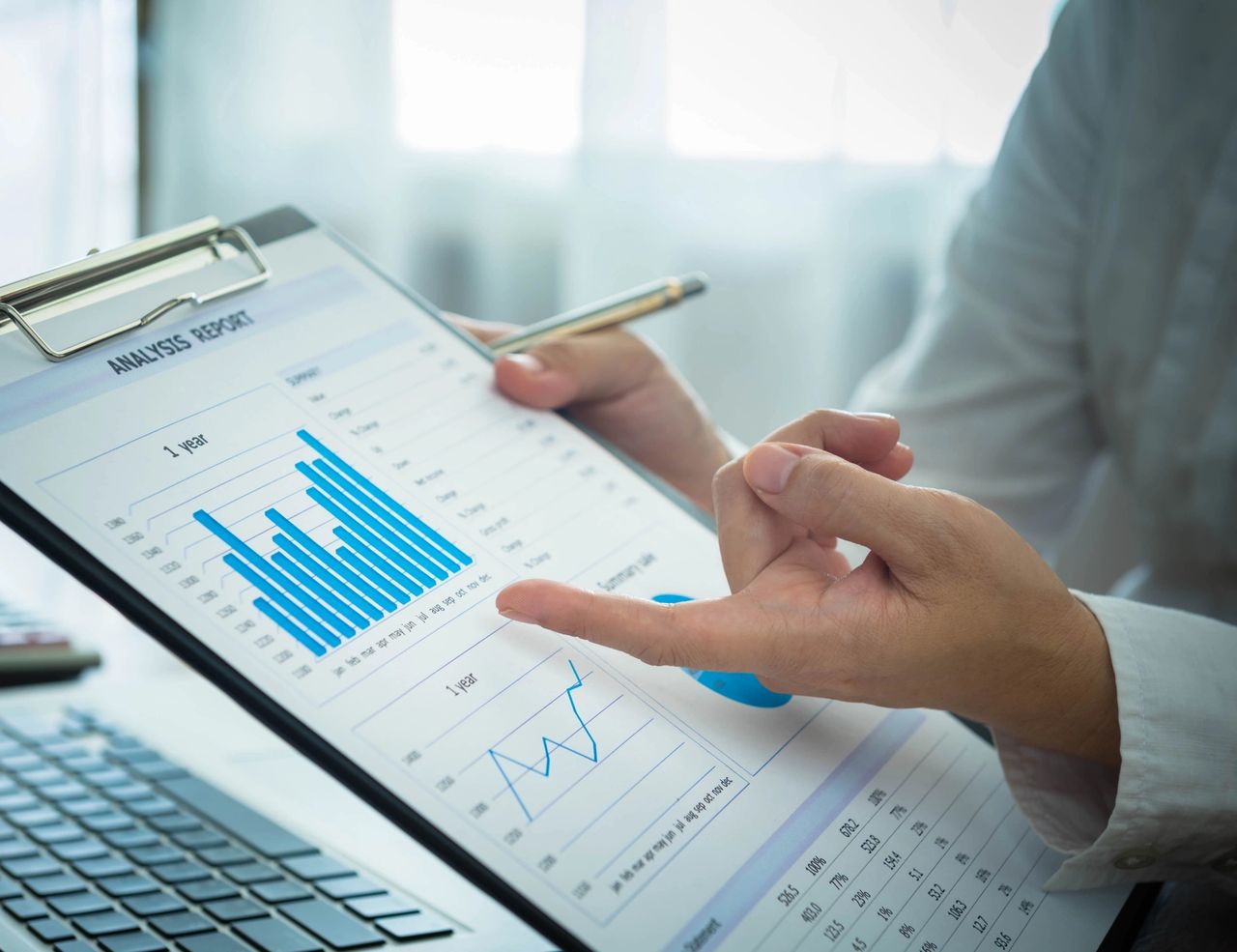 Person points out data on a clipboard of a company's performance analysis.