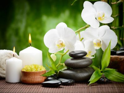 White orchids, candles, and spa stones arranged for relaxation.
